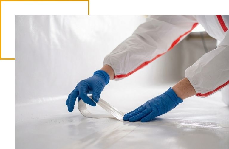 Close-up of a technician's gloved hands applying heavy-duty waterproof tape to securely seal a crawl space vapor barrier.
